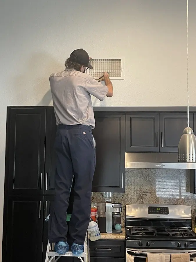 Technician inspecting an air vent during HVAC service in Brownfields